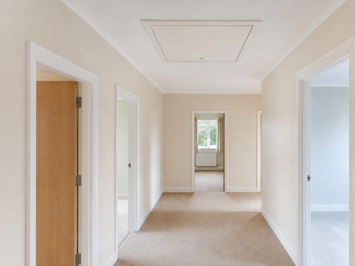 A wide loft hatch set centrally in a bungalow hallway ceiling with clear space around it