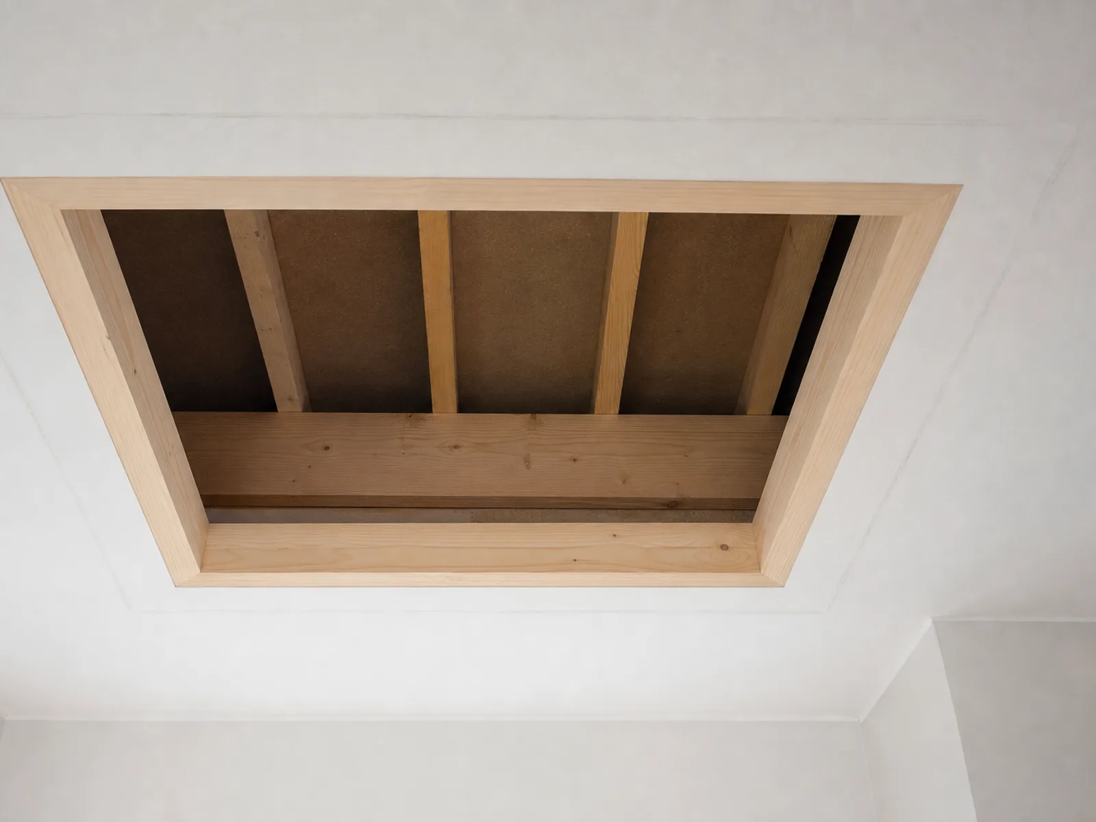 A freshly enlarged loft hatch opening in a white ceiling with new timber lining fitted around all four sides